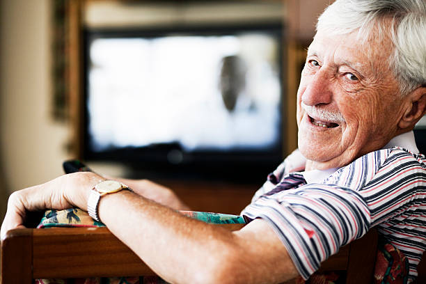 cheerful-old-man-looks-round-from-watching-television-picture-id154882581