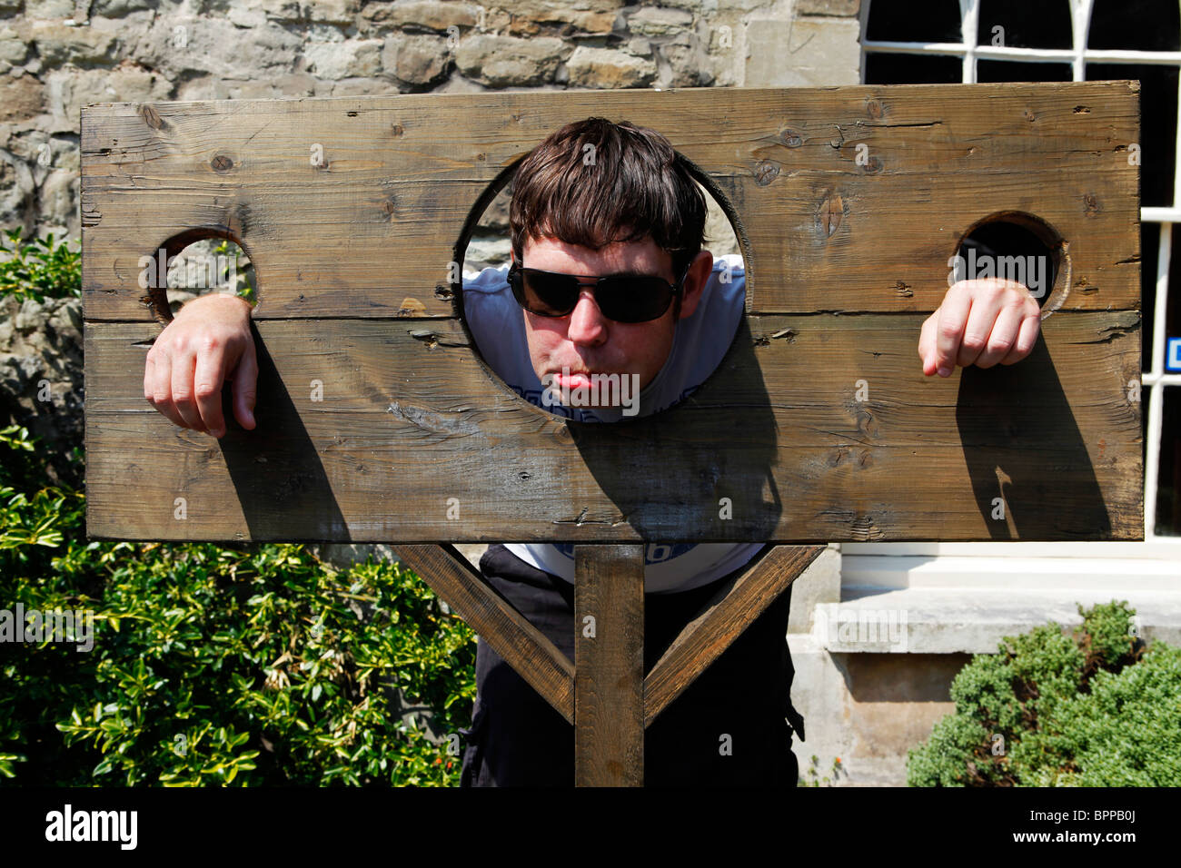 a-man-in-sunglasses-pulls-a-funny-face-while-in-stocks-in-england-BPPB0J.jpg