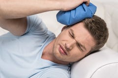 closeup-man-holding-icepack-his-head-young-experiencing-pain-white-sofa-43013468.jpg
