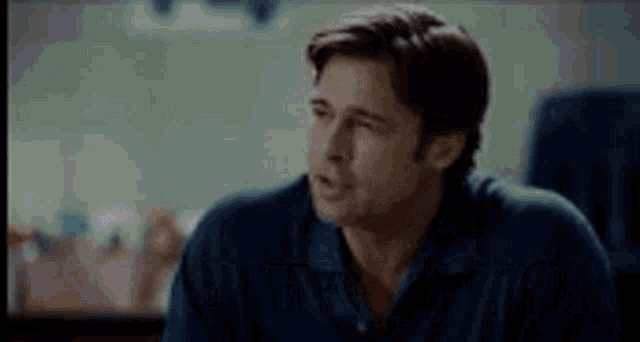 a man in a blue shirt is talking to another man in a room .