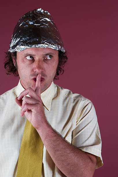 man-with-shirt-and-foil-hat-on-with-his-finger-to-his-mouth-picture-id124674841
